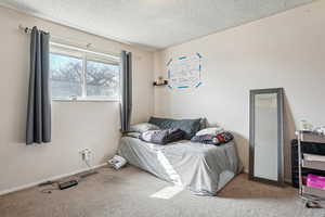 Carpeted bedroom with a textured ceiling and baseboards