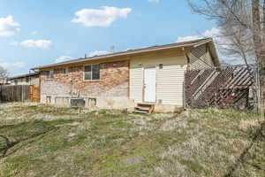 Rear view of house with brick siding, entry steps, and fence