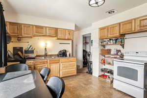 Kitchen featuring electric range, visible vents, brick patterned floor, a sink, and open shelves