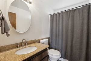 Full bath with vanity, toilet, a shower with curtain, and a textured wall