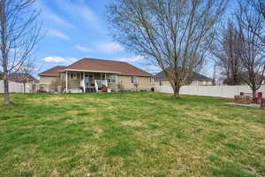Rear view of property featuring fence private yard, covered porch, and a yard