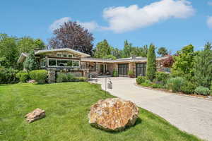 View of front of home with concrete driveway, a garage, a front yard, and stone siding