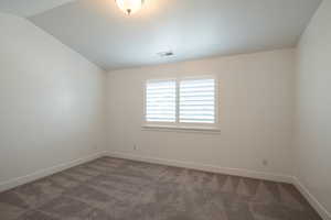 Unfurnished room featuring baseboards, lofted ceiling, visible vents, and carpet flooring