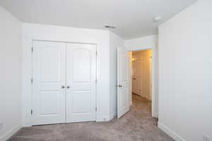 Unfurnished bedroom with visible vents, baseboards, carpet, and a closet