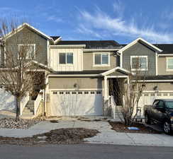Multi unit property featuring a garage, board and batten siding, driveway, and stucco siding