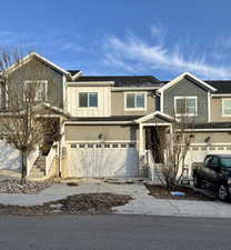 View of front facade featuring a garage, driveway, and stucco siding