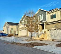 View of front of home with a garage, board and batten siding, driveway, and stucco siding