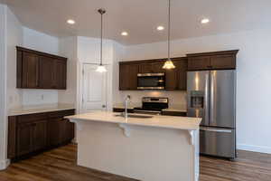Kitchen featuring a sink, dark wood-type flooring, dark brown cabinetry, and stainless steel appliances