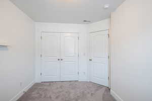 Unfurnished bedroom featuring a closet, visible vents, baseboards, and carpet floors