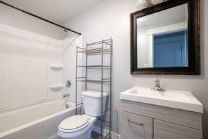 Bathroom with shower / bath combination, toilet, vanity, and a textured ceiling