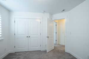 Unfurnished bedroom featuring a closet, baseboards, visible vents, and carpet floors
