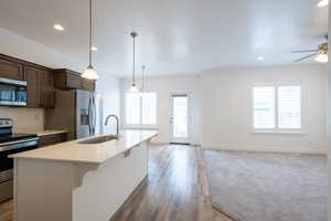 Kitchen featuring open floor plan, light countertops, appliances with stainless steel finishes, a ceiling fan, and a sink