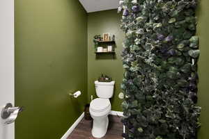 Bathroom featuring toilet, wood finished floors, and baseboards
