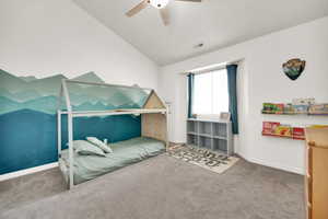 Carpeted bedroom with lofted ceiling, baseboards, visible vents, and ceiling fan