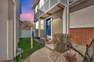 Entrance to property featuring fence and stucco siding