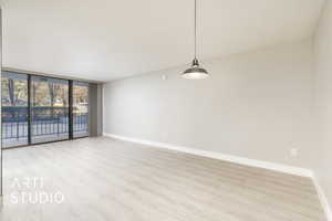 Spare room featuring a wall of windows, wood finished floors, and baseboards