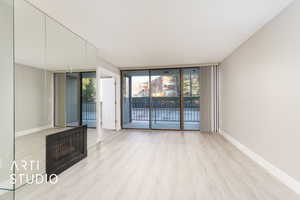 Unfurnished living room featuring wood finished floors, baseboards, and expansive windows