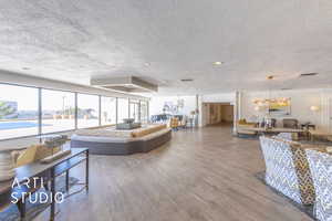 Living area with a notable chandelier, a textured ceiling, visible vents, and wood finished floors