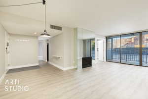 Unfurnished living room featuring visible vents, baseboards, expansive windows, a fireplace, and wood finished floors