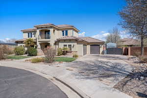 Mediterranean / spanish-style house featuring a tile roof, stucco siding, a balcony, driveway, and a gate