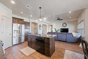 Kitchen with visible vents, black dishwasher, arched walkways, stainless steel fridge, and a sink