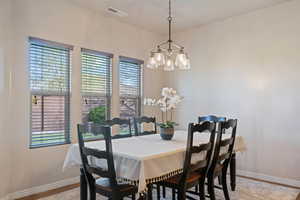 Dining area with visible vents, baseboards, a notable chandelier, and wood finished floors