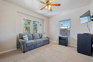 Carpeted living room with visible vents, a textured ceiling, baseboards, and a ceiling fan