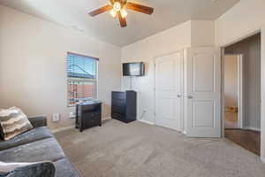 Carpeted living room with lofted ceiling, baseboards, visible vents, and ceiling fan