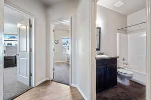 Full bathroom featuring toilet, wood finished floors, shower / bath combination, baseboards, and vanity