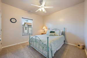 Carpeted bedroom with visible vents, ceiling fan, and baseboards