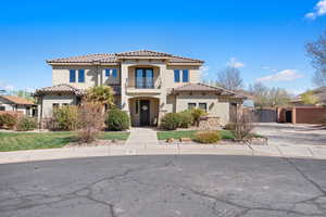 Mediterranean / spanish-style house with a tiled roof, a balcony, stucco siding, and a gate