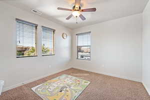 Spare room with baseboards, a ceiling fan, visible vents, and light carpet