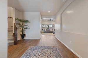 Corridor with stairway, arched walkways, baseboards, and wood finished floors