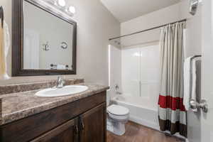 Full bathroom featuring vanity, toilet, shower / tub combo with curtain, and wood finished floors