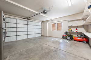 Garage featuring a garage door opener and freestanding refrigerator