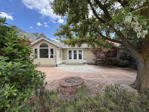 Rear view of property featuring french doors, stucco siding, a patio, and a fire pit