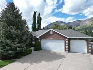Ranch-style home featuring brick siding, a garage, concrete driveway, and a mountain view