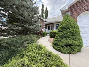 View of side of property with brick siding, a garage, and roof with shingles