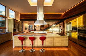 Kitchen with modern cabinets, appliances with stainless steel finishes, a breakfast bar, and hardwood / wood-style flooring