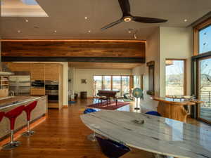Dining space with dark wood-style floors, baseboards, a high ceiling, and a ceiling fan