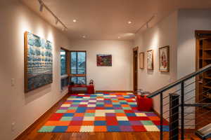 Hallway featuring recessed lighting, baseboards, wood finished floors, and rail lighting