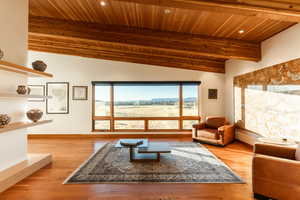 Living area featuring lofted ceiling with beams, wood ceiling, wood finished floors, and baseboards