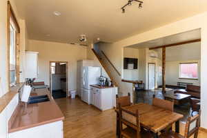 Dining space featuring light wood finished floors, vaulted ceiling with beams, stairway, a wall unit AC, and recessed lighting