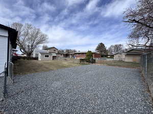 View of yard featuring an outbuilding, fence, and a residential view