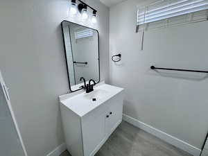 Bathroom featuring vanity, wood finished floors, and baseboards