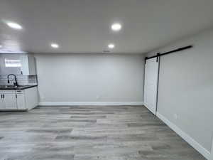 Interior space with a sink, a barn door, light wood-type flooring, and baseboards