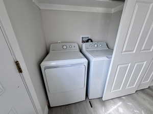 Laundry area featuring washing machine and clothes dryer, laundry area, and wood finished floors
