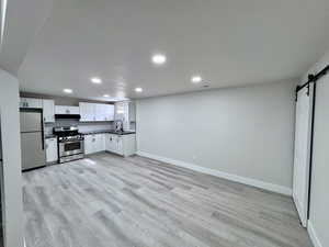 Kitchen featuring a sink, dark countertops, a barn door, appliances with stainless steel finishes, and decorative backsplash