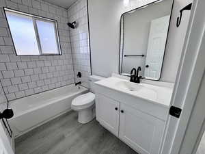 Bathroom with vanity, toilet, wood finished floors, and shower / bath combination