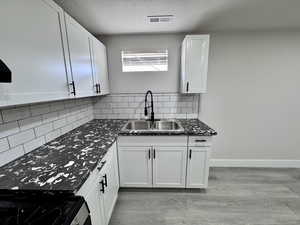 Kitchen featuring visible vents, a sink, dark countertops, stainless steel range with gas cooktop, and light wood finished floors